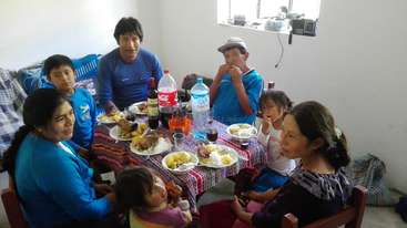 La imagen muestra a un grupo de personas reunidas en torno a una mesa, probablemente celebrando una ocasión especial, con un ambiente festivo y un sentimiento de comunidad y unión.