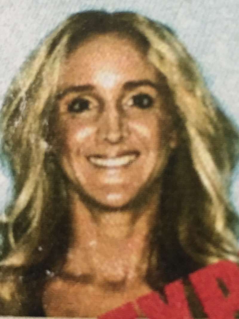 The image is a close-up of a woman\'s face with long blonde hair, wearing a red top, set against a light blue background.