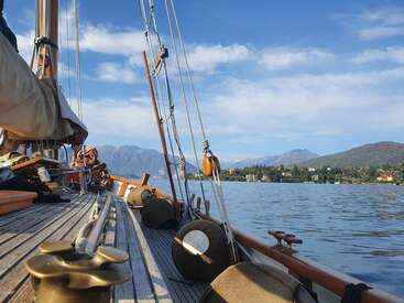 L'image représente une scène sereine d'un voilier sur un lac, avec un arrière-plan montagneux et un ciel bleu parsemé de nuages, évoquant un sentiment de tranquillité et d'aventure.