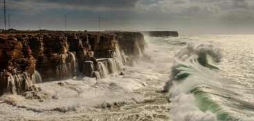 D'imposantes falaises rocheuses font face à la mer implacable et aux puissantes vagues qui s'abattent sur elles. L'eau tombe en cascade à flanc de falaise, créant des chutes d'eau spectaculaires et brumeuses par temps agité.