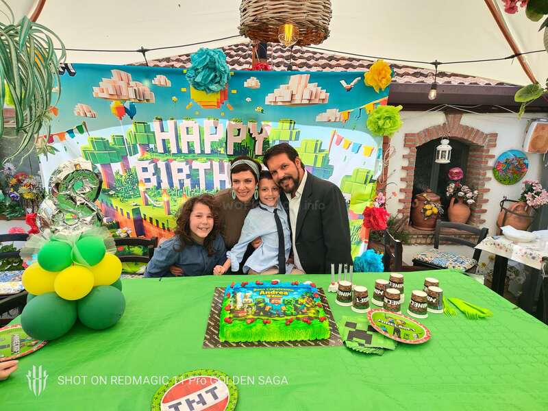 Eine Familie feiert die Minecraft-Geburtstagsparty eines Kindes. Bunte Dekorationen, eine Torte, Luftballons und strahlende Gesichter prägen die festliche Stimmung unter einem geschmückten Festzelt.