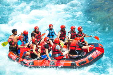 Eine Gruppe abenteuerlustiger Menschen mit Schwimmwesten und Helmen paddelt gemeinsam in einem großen Schlauchboot durch die turbulenten, leuchtend blauen Stromschnellen. Teamwork und Aufregung!