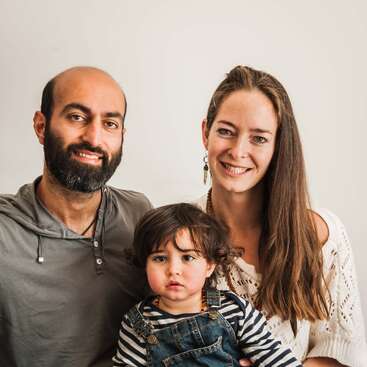 The image depicts a family of three, comprising a man, woman, and child, posing together for a photo, exuding a sense of warmth and togetherness.