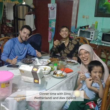 Cuatro personas, incluido un niño, disfrutan alegremente de una cena en una acogedora casa. La mesa está llena de comida, creando un ambiente cálido y acogedor.