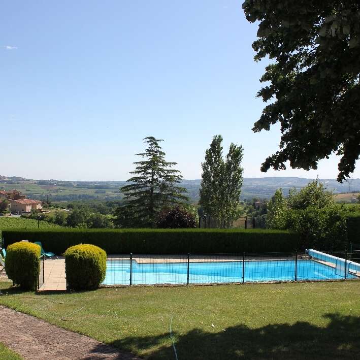 Das Bild zeigt einen ruhigen Hinterhof mit einem Pool, umgeben von üppigem Grün und einer malerischen Landschaft vor einem klaren blauen Himmel.