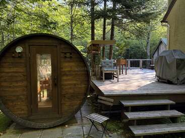 Im gemütlichen Hinterhof gibt es eine runde Holzsauna, eine Terrasse mit Gartenmöbeln, einen Grill und einen üppigen grünen Wald, der einen friedlichen und entspannenden Rückzugsort in der Natur bietet.