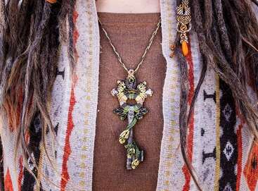 L'image montre la poitrine d'une personne ornée d'un collier frappant et d'un cardigan vibrant, mettant en évidence un mélange unique de style et de personnalité.