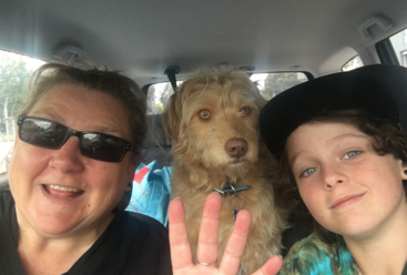 Das Bild zeigt einen Hund und eine Katze, die auf dem Boden sitzen, wobei der Hund auf der linken und die Katze auf der rechten Seite in die Kamera schauen. Der Hintergrund ist eine schlichte Wand.