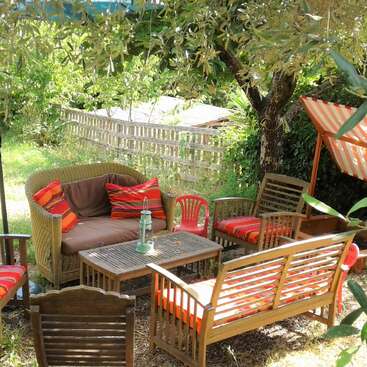 L'image représente un cadre extérieur serein, avec un patio doté d'une table et de chaises, entouré d'une pelouse verdoyante, évoquant un sentiment de tranquillité et de détente.
