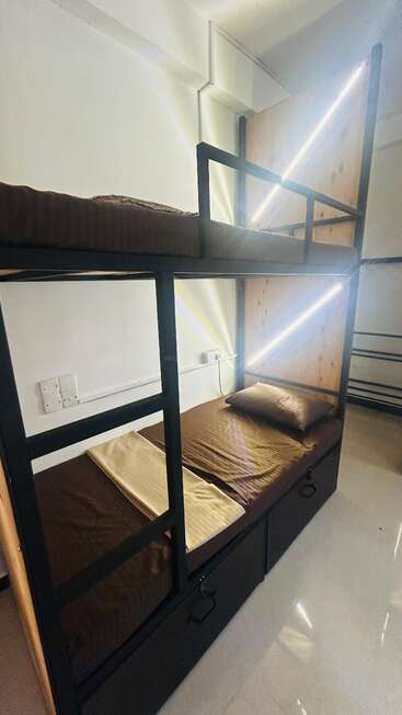 This image shows a modern, clean bunk bed with brown bedding and wooden panels. LED lights illuminate each level, and storage drawers are built-in below.