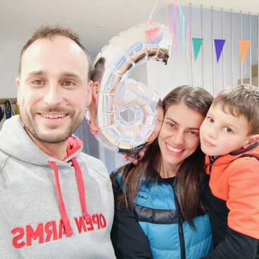 L'image montre une famille de trois personnes posant pour un selfie, avec le père à gauche, la mère au milieu et l'enfant à droite, tous souriants.