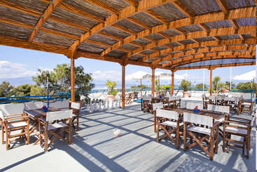 The image depicts a serene outdoor setting, featuring a covered patio with a table and chairs, surrounded by a fence, with a grassy area and trees in the background.