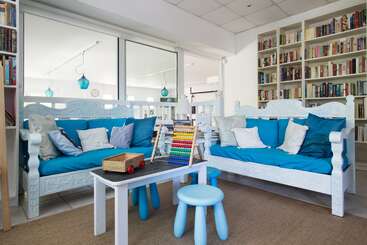 The image depicts a cozy room with a table and chairs, featuring a bookshelf, a lamp, and a window, evoking a sense of warmth and comfort. The room is well-lit and inviting.