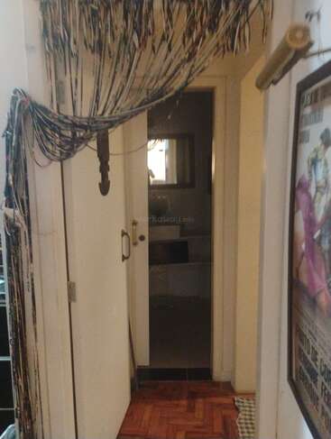 A narrow hallway with tangled cables draped across the ceiling and down the wall. An open door leads to another room, and a poster hangs nearby.