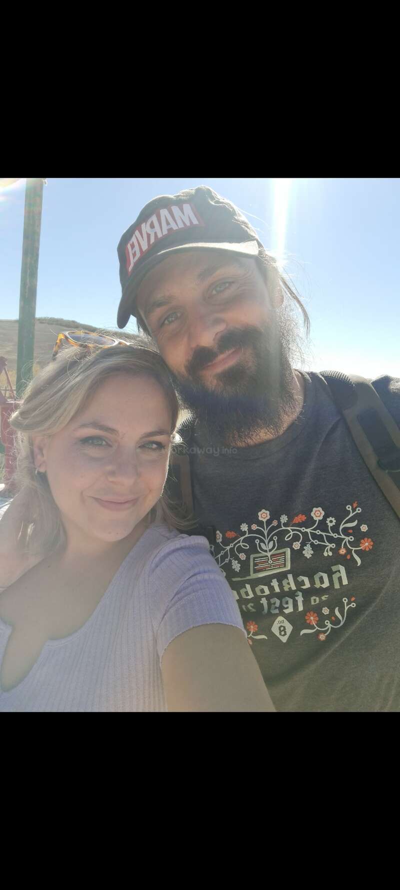 A imagem mostra uma fotografia de duas pessoas, com a pessoa à esquerda usando uma camisa branca e a pessoa à direita usando uma camisa de cor escura.