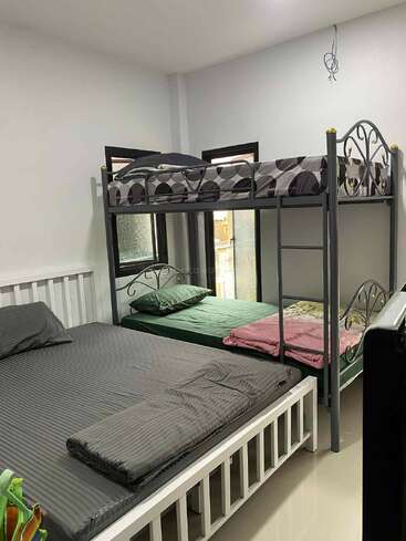 Dieses Bild zeigt ein kleines Schlafzimmer mit einem Etagenbett und einem Doppelbett. Die Betten haben ordentliches Bettzeug in grauen und grünen Farben.