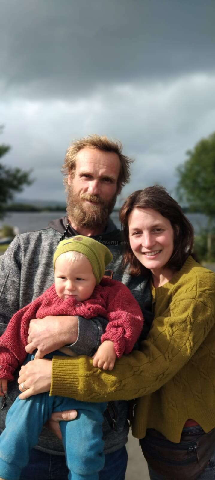 A imagem mostra uma família de três pessoas posando para uma foto, com os pais e o filho juntos, transmitindo um senso de unidade e união.