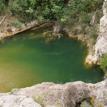 L'image représente un cadre naturel serein, avec une étendue d'eau tranquille et une petite île, entourée d'une végétation luxuriante et d'un ciel bleu clair, évoquant un sentiment de paix et de tranquillité.