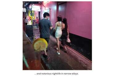 A group walks through a narrow, neon-lit alley at night. A drink with a lemon slice sits in the foreground, highlighting the lively nightlife atmosphere.