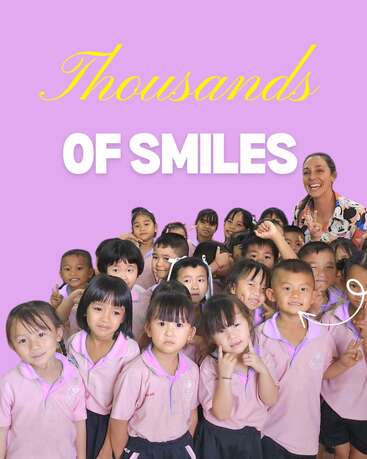 A cheerful group of young children in pink uniforms pose with their smiling teacher against a purple background, under the joyful text “Thousands of Smiles.”