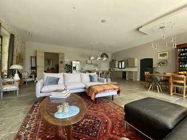 Este acogedor espacio abierto cuenta con una cocina moderna, cómodos asientos, una alfombra colorida, muebles elegantes, grandes ventanas y un atractivo comedor con luz natural.