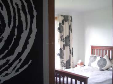 The image depicts a bedroom with a bed, nightstand, and window, featuring a zebra-print wall and a wooden headboard, with a white and gray color scheme.