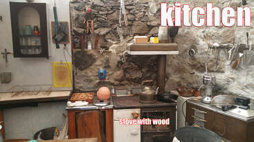 The image depicts a kitchen with a stove, sink, and cabinets, featuring a large island with a sink and a dining table with chairs, set against a neutral background.