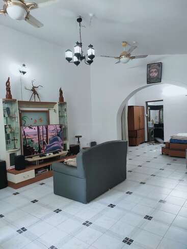 The image depicts a spacious room with white walls and tiled floors, featuring a TV stand, couch, and archway leading to another room with a washing machine and laundry area.