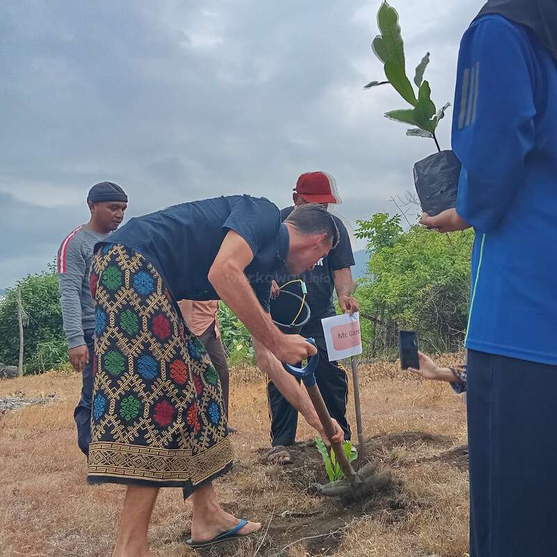 L'image représente un groupe de personnes en train de planter un arbre dans un champ, une personne tenant une pelle et une autre une plante. La scène se déroule dans un ciel nuageux.