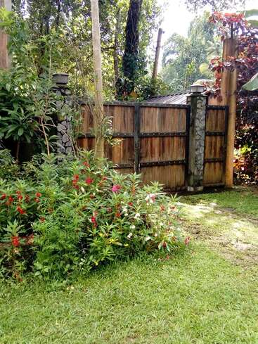 The image depicts a serene garden scene featuring a wooden gate, lush greenery, and vibrant flowers, evoking a sense of tranquility and natural beauty.