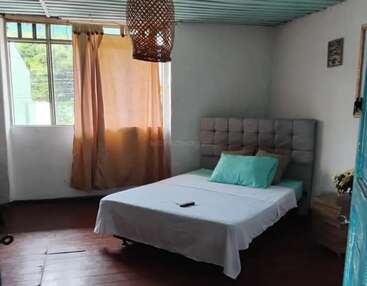 Dieses gemütliche Schlafzimmer verfügt über ein Doppelbett mit einem gepolsterten Kopfteil, eine hellblaue Decke, weiche Vorhänge, Holzböden, einen Nachttisch und natürliches Sonnenlicht durch große Fenster.