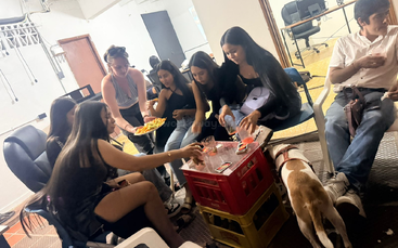 Um grupo de amigos senta e conversa dentro de casa, jogando cartas em torno de uma mesa improvisada. Comem uns petiscos e tomam uns drinks, enquanto um cachorro anda por ali.
