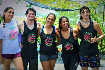 Five smiling people stand outdoors, posing together in matching "Hostel Vallarta Mexico" tank tops and casual shorts, suggesting a fun group or team-bonding event.