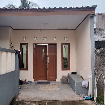 L'image représente la façade d'une maison avec une porte marron, deux fenêtres et un toit en tuiles, avec un porche en béton et un mur gris sur le côté gauche.