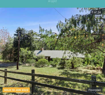 A house nestled among trees and greenery, partially hidden by foliage and a wooden fence. The property was sold on June 10, 2022. Quiet, rural setting.
