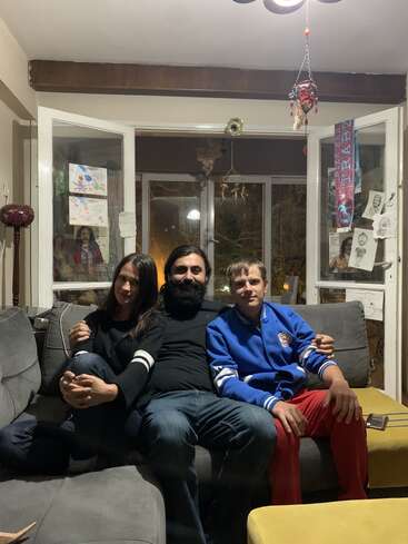 A imagem mostra uma família de três pessoas sentadas em um sofá cinza em uma sala de estar aconchegante, cercada por uma atmosfera calorosa e convidativa.