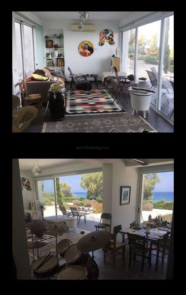 A bright, artistic living space with musical instruments, colorful rugs, eclectic furniture, glass walls, and a scenic outdoor view of trees, garden, and the sea.