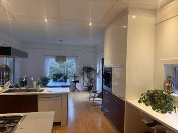 Cette photo montre une cuisine spacieuse et moderne, avec des placards blancs, un parquet, un îlot central, des plantes d'intérieur, une grande table à manger, de la lumière naturelle et une décoration minimaliste dans toute la pièce.