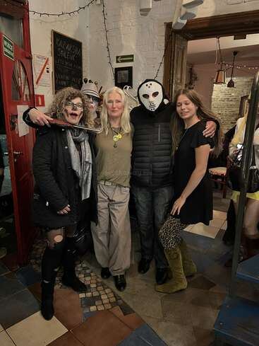 A group of four people are dressed in costumes for a party or event. They are standing together indoors, smiling and posing for the camera.