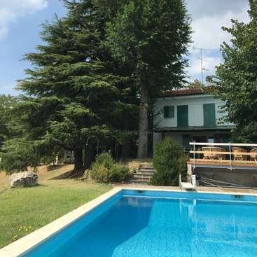 Das Bild zeigt einen ruhigen Hinterhof mit einem Pool, einem Haus und üppigen Bäumen, die ein Gefühl von Entspannung und Ruhe vermitteln.