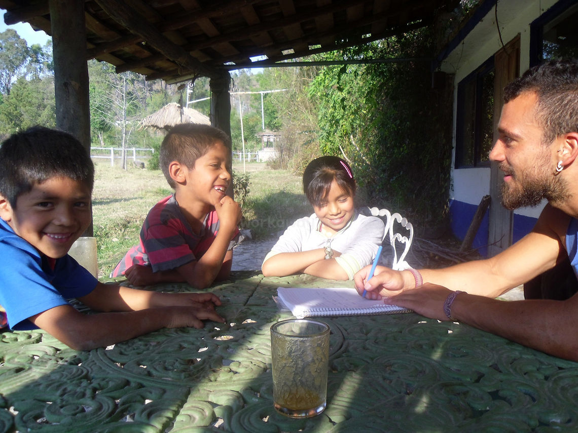 local children teaching workawayer new language while traveller makes notes