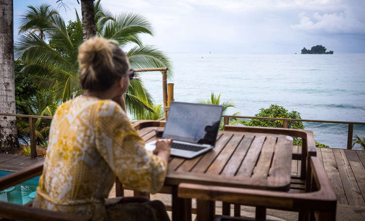 digital nomad on laptop admiring ocean view outdoors