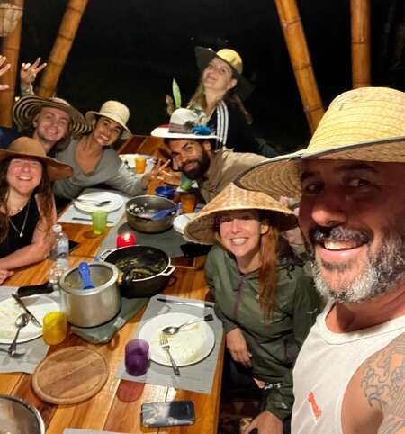 world travellers and volunteers around a table smiling at camera after a shared meal