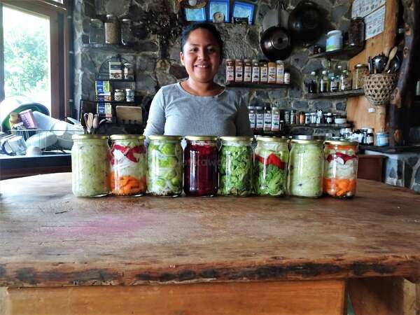 woman standing in kitchen with jars of pickled vegetables in front of her