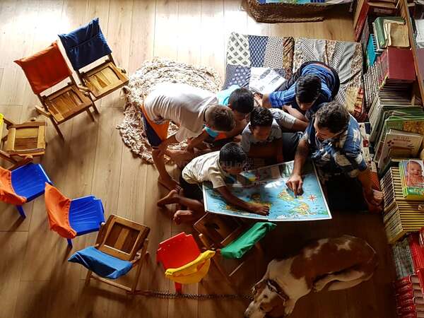 birds eye view of group of children and workawayer looking at a map together