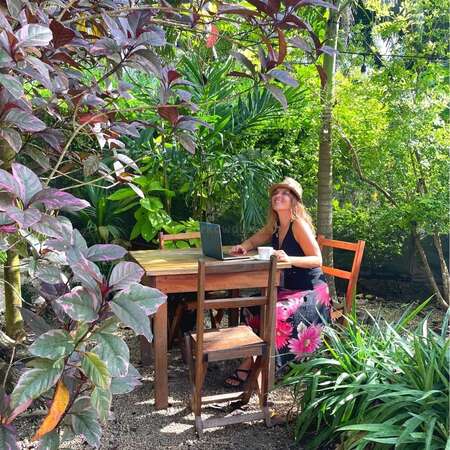 solo woman with laptop and mug gazing at trees around her