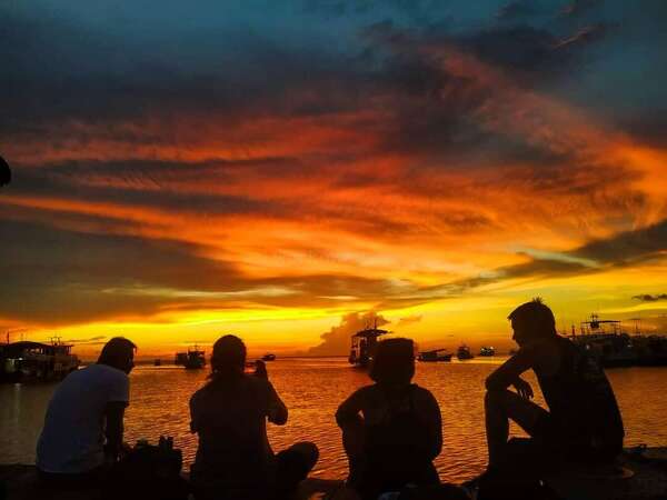 four travellers gazing over sunset and beach