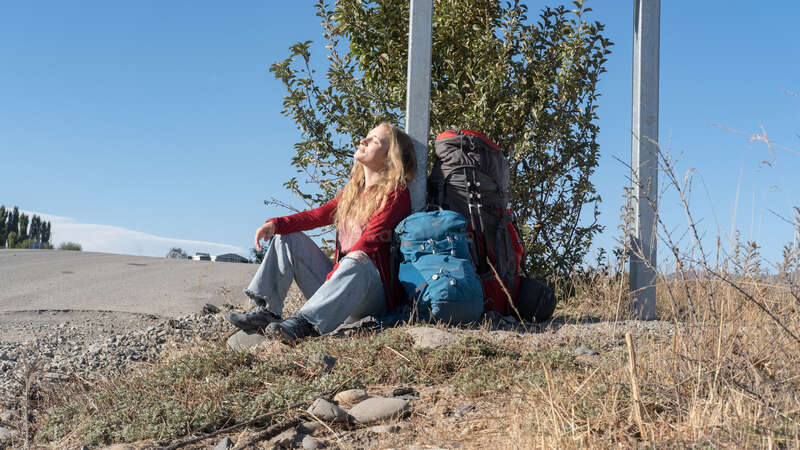 solo female traveller enjoying the sun with backpacks on the floor