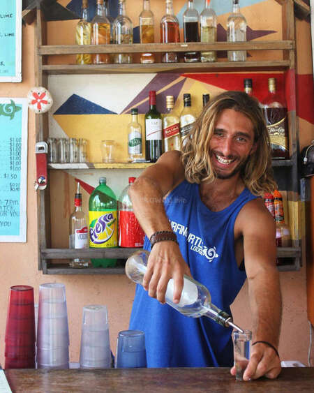 man pouring drink behind bar