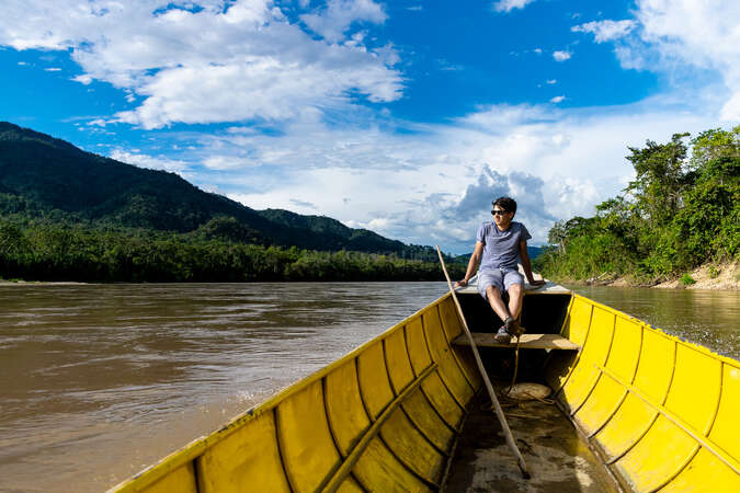 solo man on boat sailing through a river